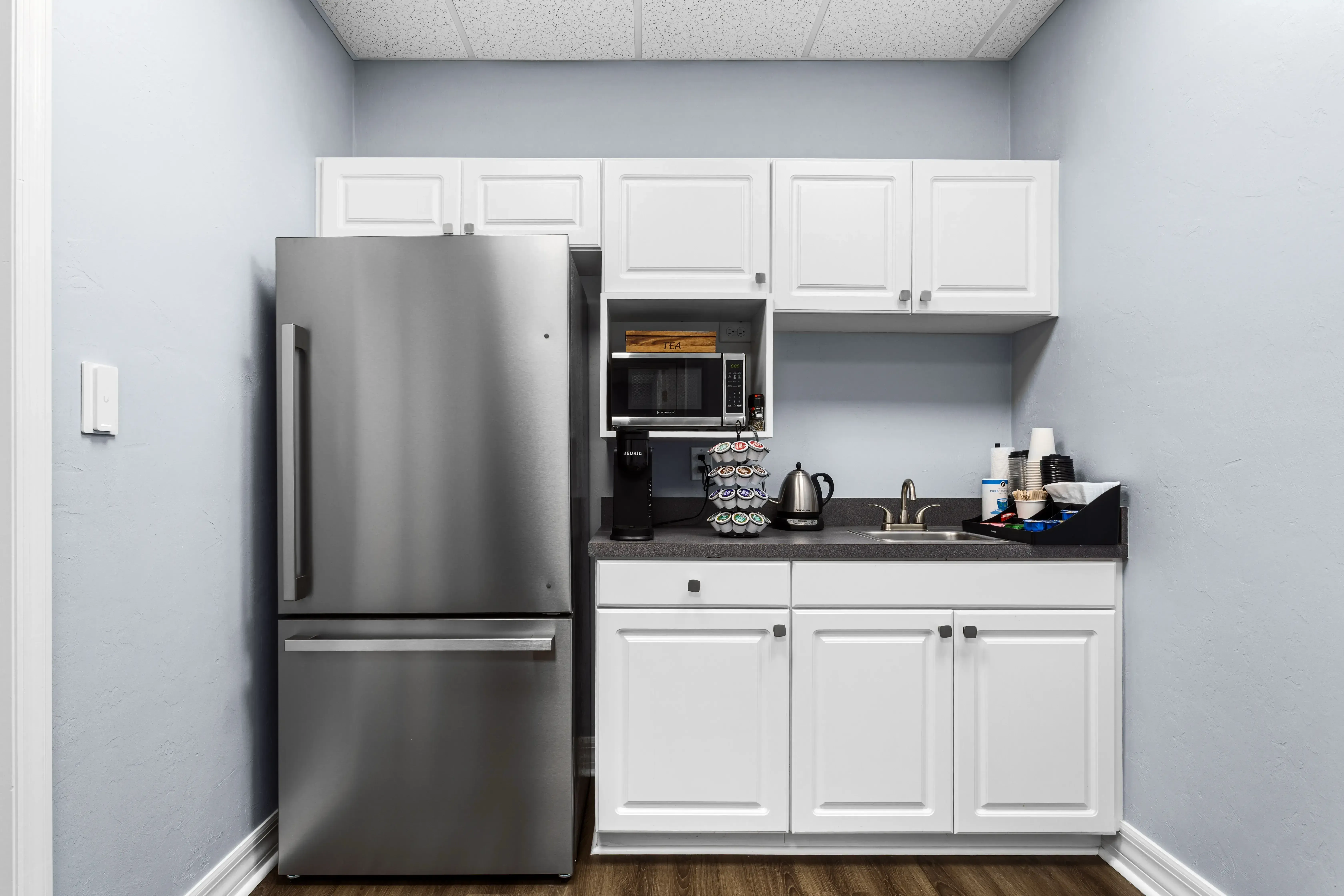 Kitchenette with refrigerator, coffee maker, microwave, and refreshments for guests at ProSpace Gainesville